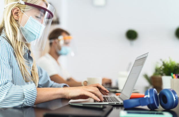 Young people working in co-working creative space wearing surgic