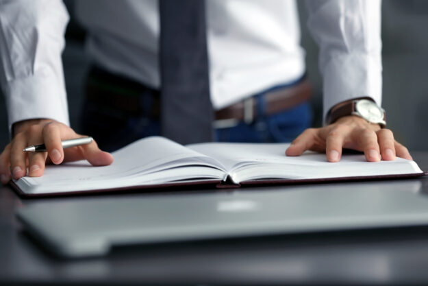Businessman holding notepad on desk
