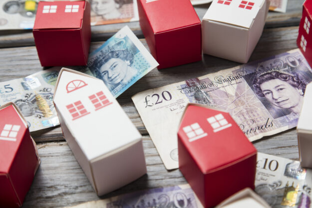 LONDON, UK – Circa March 2019: Housing cost. Paper toy house with British currency notes