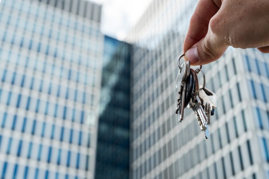 Keys,In,Hand,Against,Modern,Office,Skyscrapers,,Real,Estate